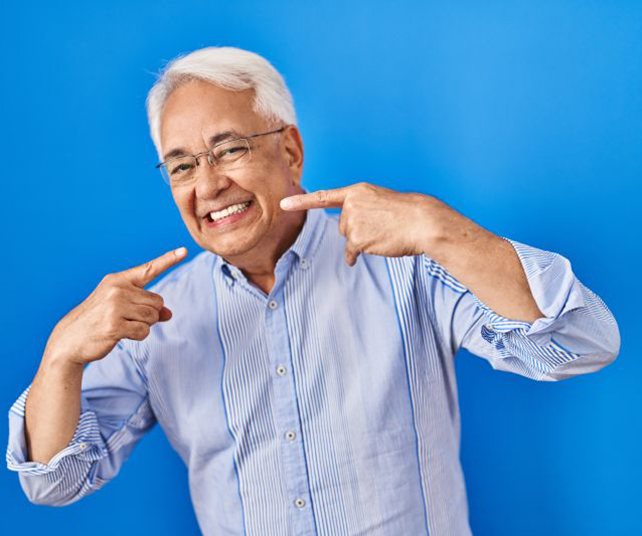 Happy senior man pointing at his teeth