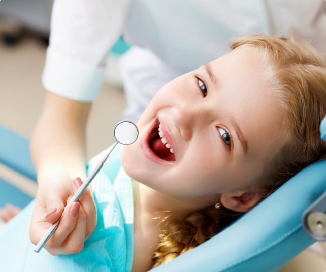 Child receiving dental checkup and teeth cleaning for kids