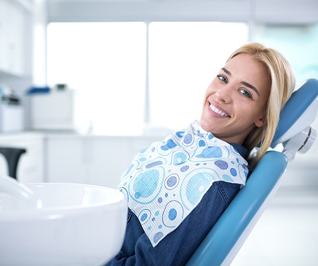 Smiling female patient in dentist’s chair