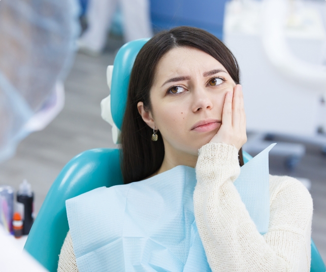 Woman holding cheek before emergency dentistry treatment