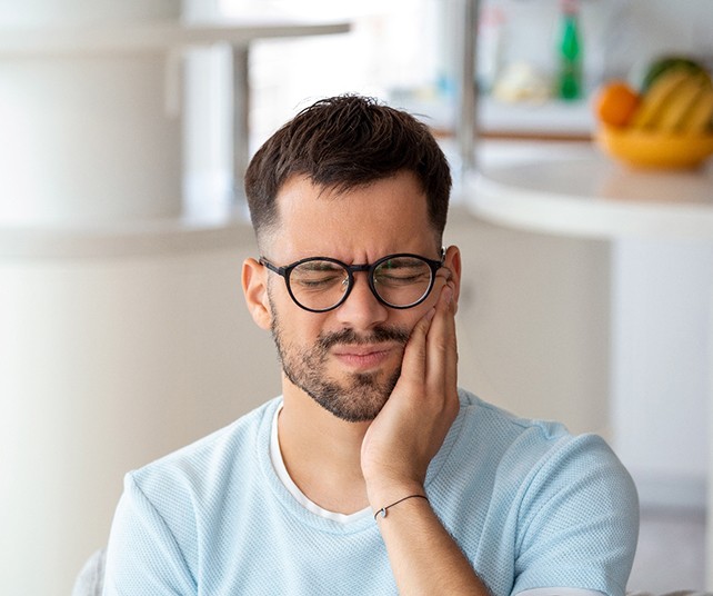 Man with black glasses experiencing toothache