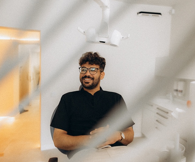 Patient with black glasses smiling in treatment chair