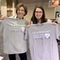 Two dental team members holding up matching shirts